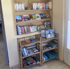 Benouchon Bücherregal mit Büchern, Broschüren und Spielen.